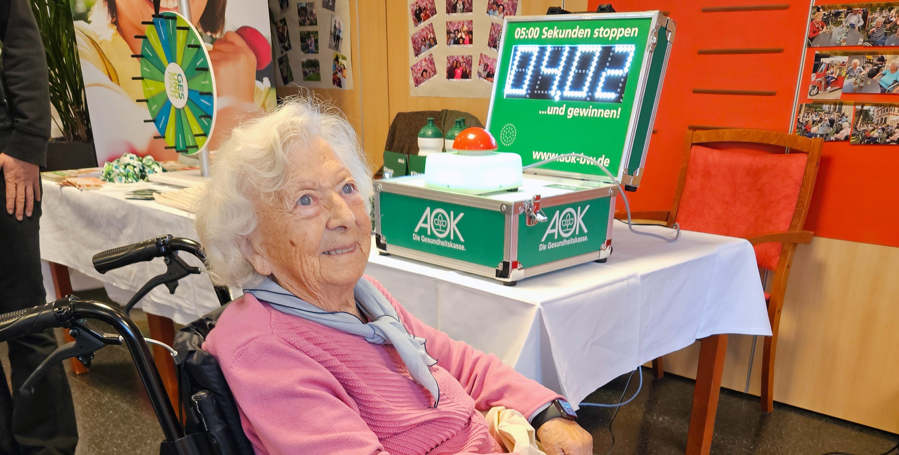 Seniorin im Rollstuhl vor AOK-Stand