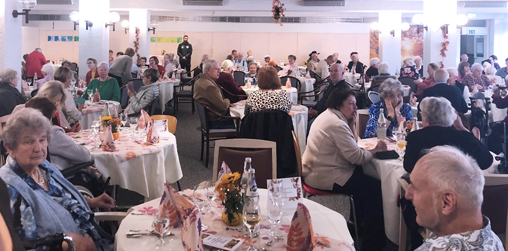 Bewohnende und Gäste sitzen an herbstlich dekorierten Tischen und genießen das gemeinsame Mittagessen beim Herbstempfang im Wohnstift Mönchfeld.
